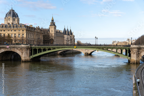 A bridge spans a river in a city with a large building in the background