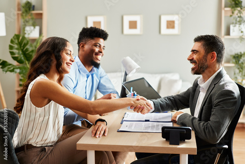 Young couple makes a deal with an agent in the office and does handshake