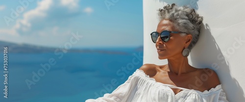 A beautiful African black senior woman sits with a sea view and enjoys her summer vacation. Travelling advertising. Active happy life.