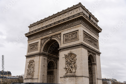 The Arc de Triomphe is a large, white arch with intricate carvings and statues © oybekostanov