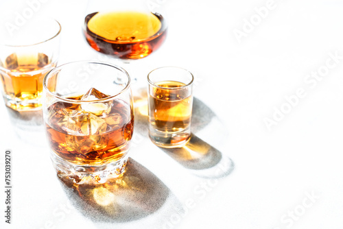 Strong alcohol drink in different glasses at white background.