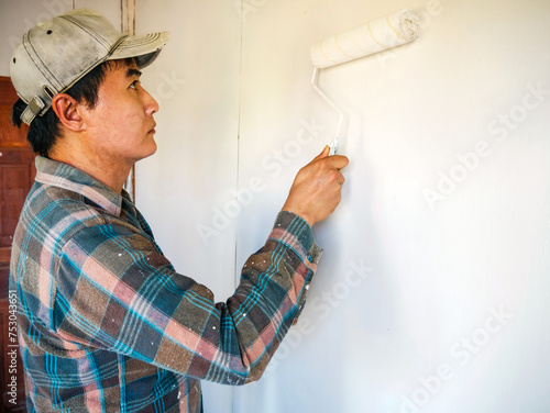 Workers painter are painting the wooden walls of the room white with paint roller,improvement home interior concept.