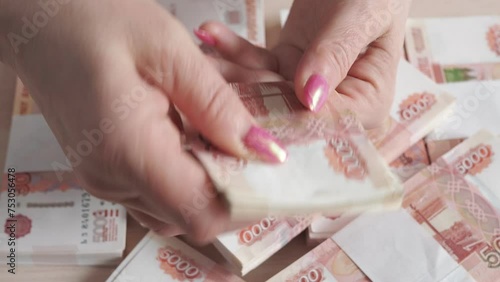 A close-up of the fingers of a hand counting five thousandth banknotes of the Russian ruble. Women's hands count Russian banknote money with a face value of 5000. photo