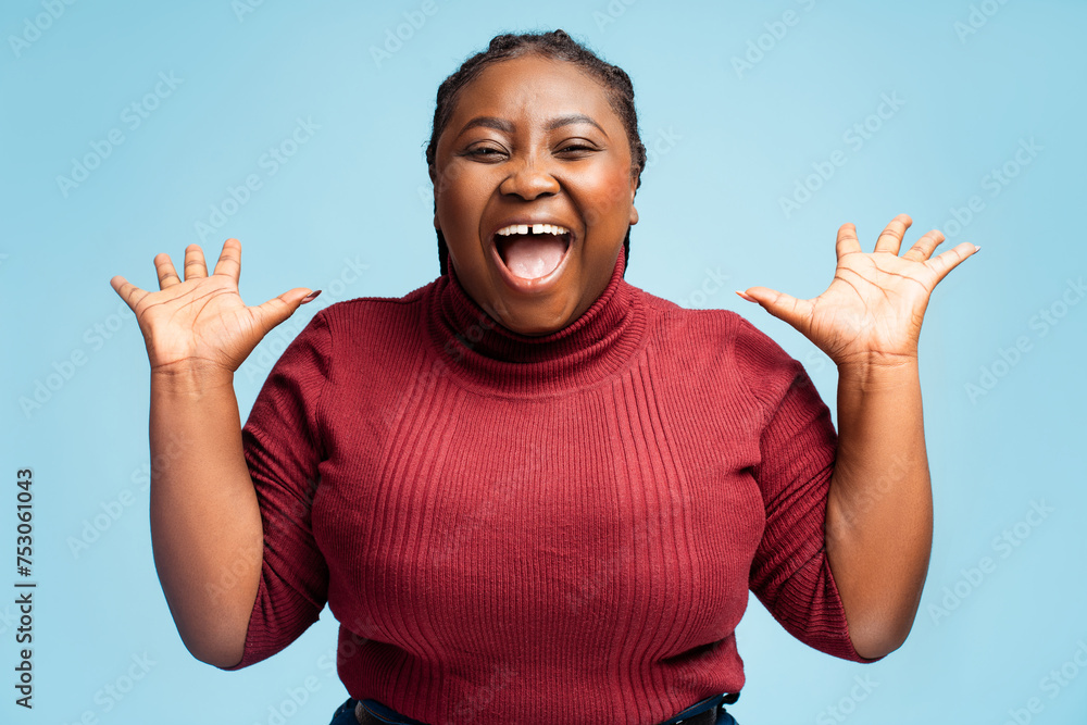 Overjoyed African American woman holding hands up with open mouth isolated on blue background