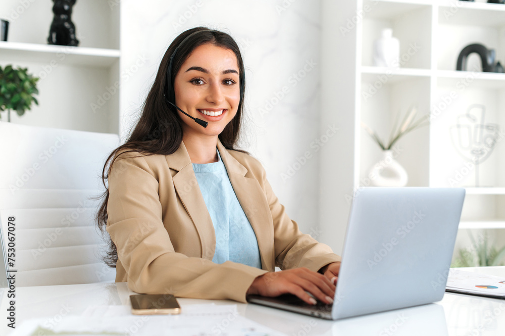 Call center, customer support service. Confident positive woman, call center operator with headset, working on support hotline in a modern office with a laptop, looking at the camera, smiling friendly Call center, customer support service. Confident positive woman, call center operator with headset, working on support hotline in a modern office with a laptop, looking at the camera, smiling friendly