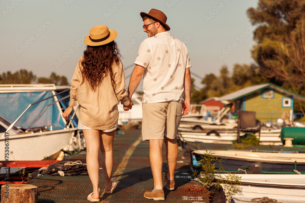 Couple in love holding hands while taking a walk on river docks Couple in love holding hands while taking a walk on river docks