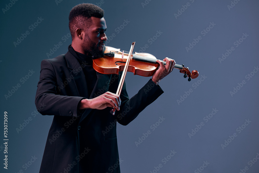Φωτογραφία Elegant african american man in suit playing violin on dark background, creating