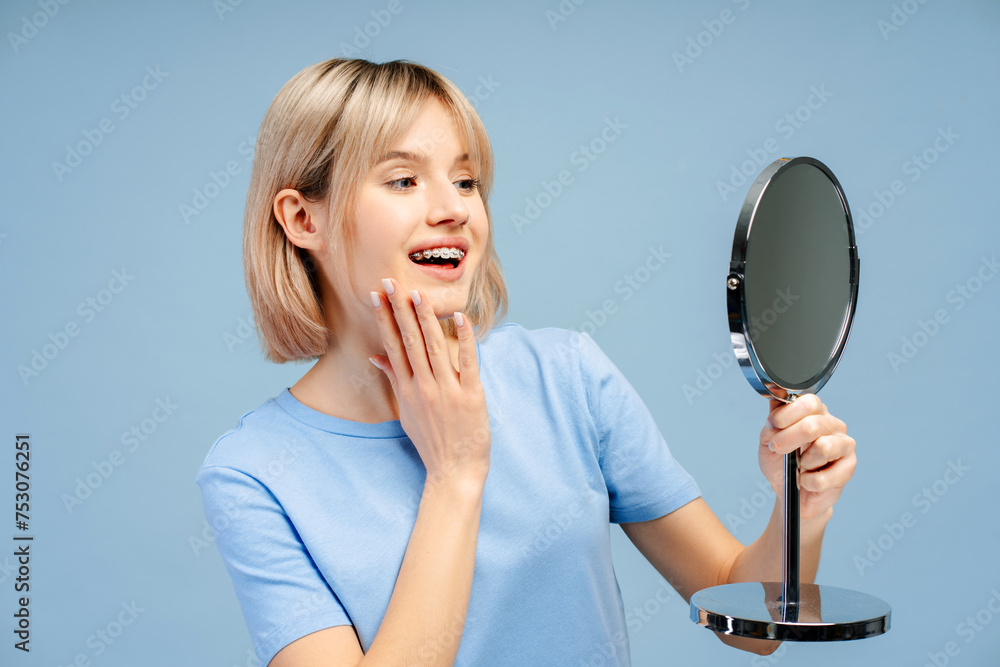 Beautiful, smiling Caucasian woman with braces holding mirror, looking in mirror Beautiful, smiling Caucasian woman with braces holding mirror, looking in mirror