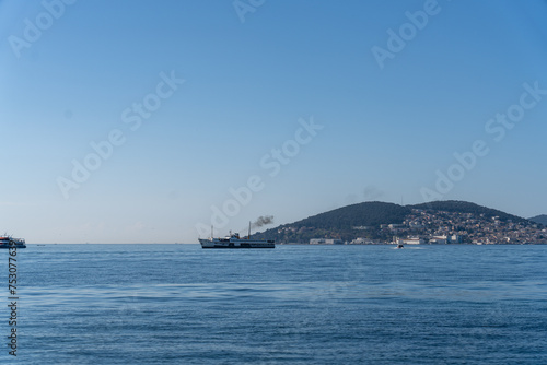 A boat is sailing in the ocean with a blue sky in the background © oybekostanov