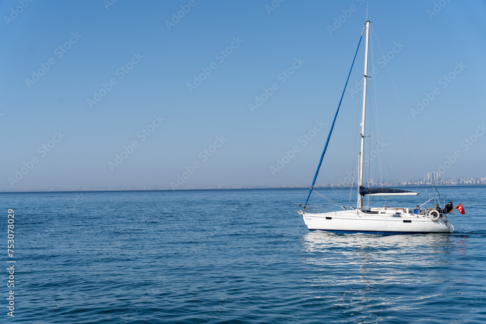 A sailboat is floating on the water in a calm sea A sailboat is floating on the water in a calm sea