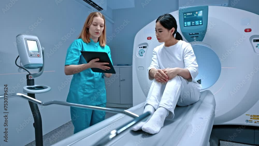 Doctor holding tablet and showing result of MRI. Patient lying at MRI capsule. MRI cabinet. Modern equipment in private clinic. Doctor talking to patient after procedure. MRI examination. Doctor holding tablet and showing result of MRI. Patient lying at MRI capsule. MRI cabinet. Modern equipment in private clinic. Doctor talking to patient after procedure. MRI examination.
