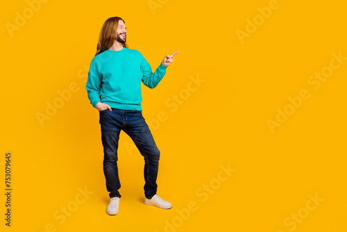 Full body photo of positive young man look direct finger empty space ad isolated on yellow color background