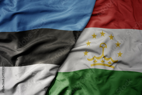 big waving national colorful flag of tajikistan and national flag of estonia.