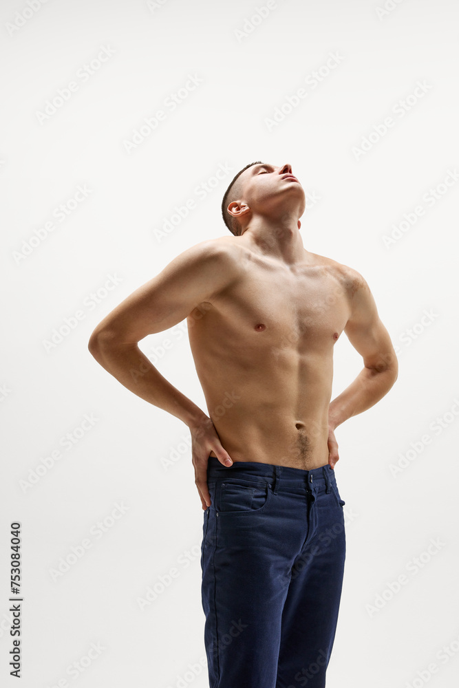 Shirtless handsome young man with muscular, relief, body posing in jeans isolated over white studio background. Concept of sportive lifestyle, body and heath care, youth