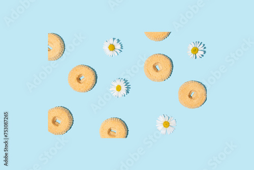 Cookies and white daisy flowers on a pastel blue background. Minimal pattern.