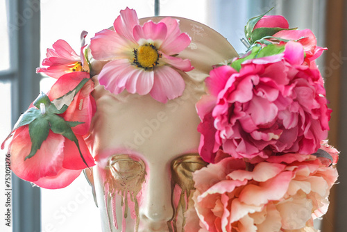 Beautiful young woman's face and bright flowers. Plaster antique bust of Venus in a floral wreath. The sculpture is the embodiment of spring and nature.