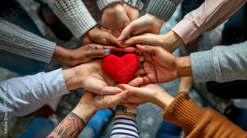 Diverse group of people's hands coming together to support a plush red heart © MP Studio