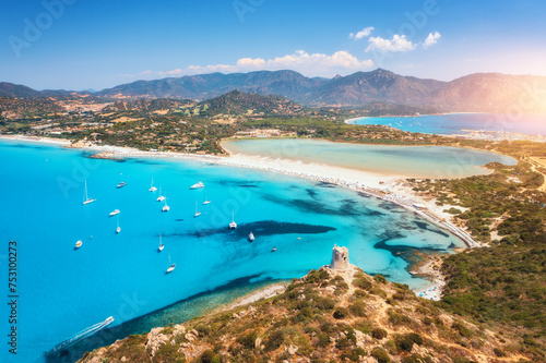 Aerial view of white sandy beach, old tower on the hill, sea bay, mountains at sunset in summer. Porto Giunco in Sardinia, Italy. Top view of blue sea with clear water, white sand, mountains © den-belitsky