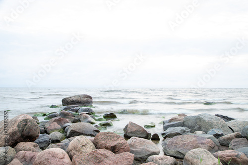coastline with red and green rocks on the front and breezy waves with light grey sky on the back
