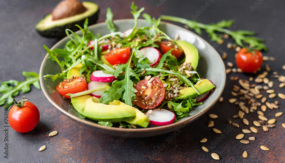 Healthy salad of fresh vegetables, red tomatoes, avocado, arugula, radish and seeds in plate.