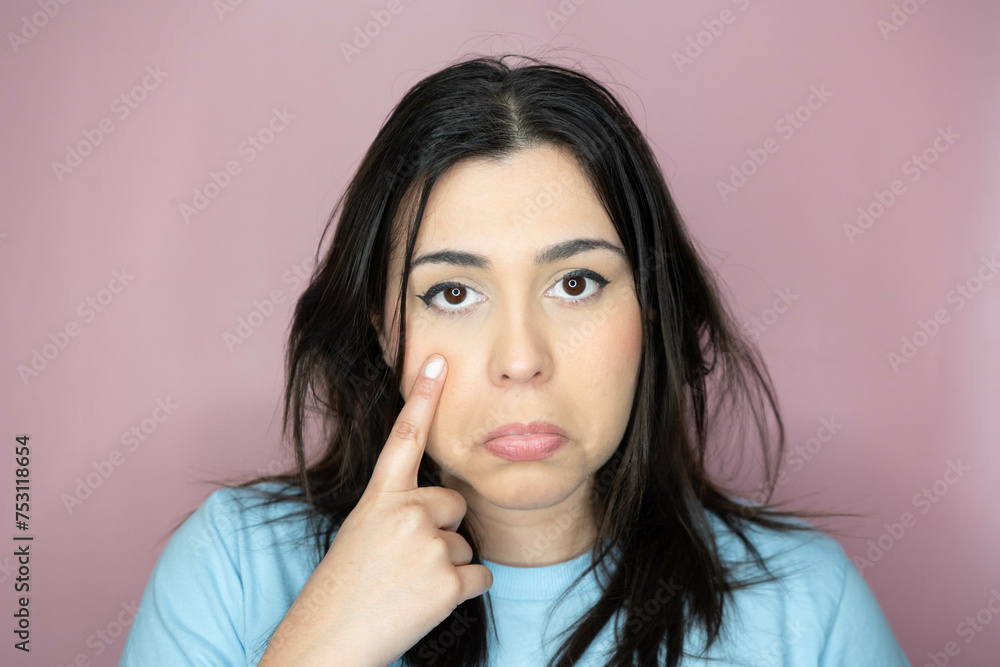 Close-up image of an attractive young woman with long hair and a playful look, making an amused expression, smiling and pointing with her hands. Close-up image of an attractive young woman with long hair and a playful look, making an amused expression, smiling and pointing with her hands.