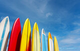 Set of differently colored surfboards stacked by the ocean