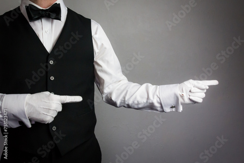 Portrait of Waiter or Butler in White Gloves and Black Vest Pointing the Way. Concept of Hospitality and Professional Courtesy.