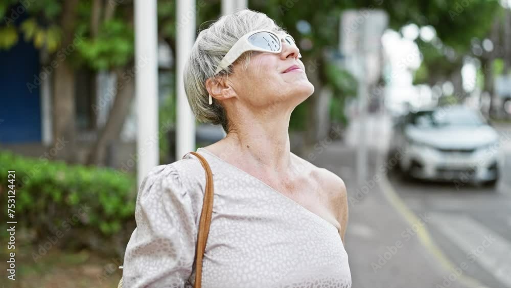 Elegant mature woman with grey hair and sunglasses walks confidently on a city street. Elegant mature woman with grey hair and sunglasses walks confidently on a city street.