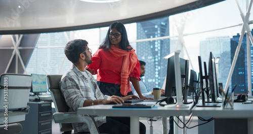 Two Young Indian Financial Advisers Having a Conversation About Stock Market Strategy Next to a Computer in a Modern Company. South Asian Managers Work in a Banking Research and Development Center