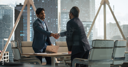 South Asians Business Partners Striking a Successful Deal at a Corporate Modern Meeting Room. Two Young Indian Businessmen Shaking Hands After a Positive Negotiation Process