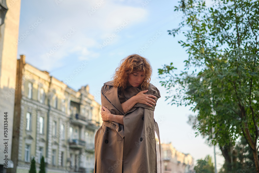 Cropped closeup portrait of a caucasian mature beautiful woman wife looking at the sun in park outdoors streets hiding from the sunset sun in sad serious mood. High quality photo
