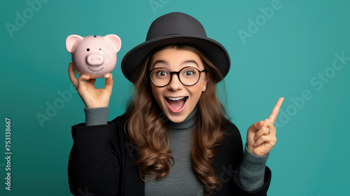 Smiling young girl holding a piggybank against blue background