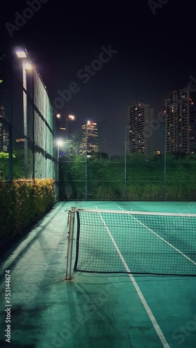 Tennis court with a net and a racket at night