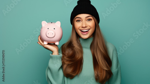 Smiling young girl holding a piggybank against blue background