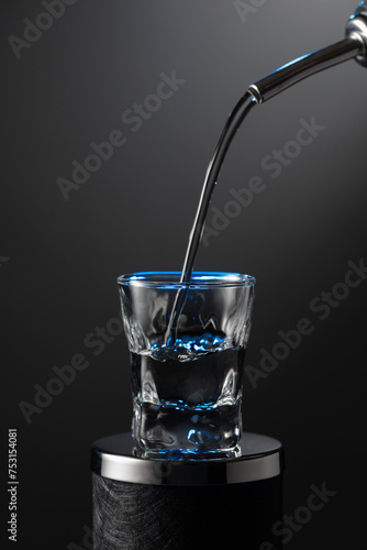 Vodka pouring from the bottle into a glass on a dark background.