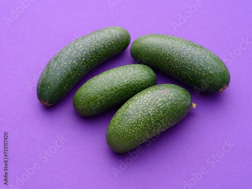 Four cocktail avocados or mini avocados on a purple background. photo