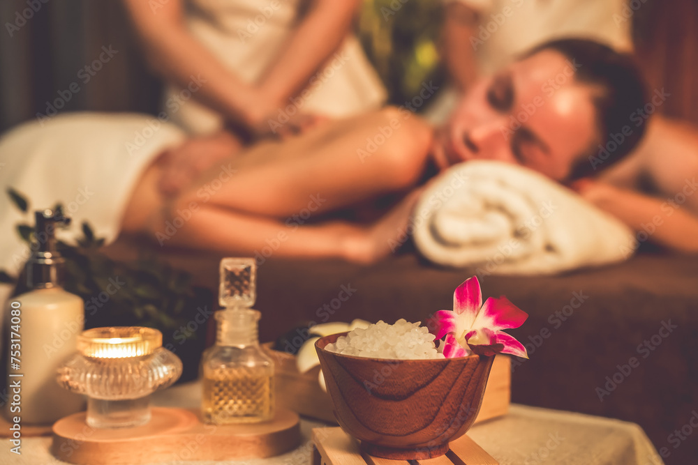 Aromatherapy massage ambiance or spa salon composition setup with focus decor candles and spa accessories on blur couple enjoying blissful aroma spa massage in resort or hotel background. Quiescent