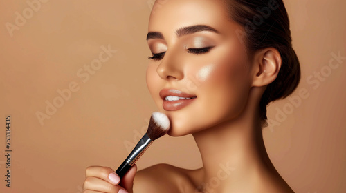 Beautiful young woman with healthy skin doing makeup with brush isolated on beige background, concept of cosmetic product, make up, healthy skin, foundation apply, skin colors, with copy space.