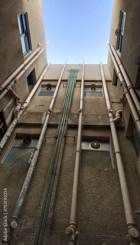 Obraz premium Residential appartment building plumbing and water supply, distribution and circulation system plastic pipes on wall. Pipelines and drainage concept. Closeup vertical bottom view