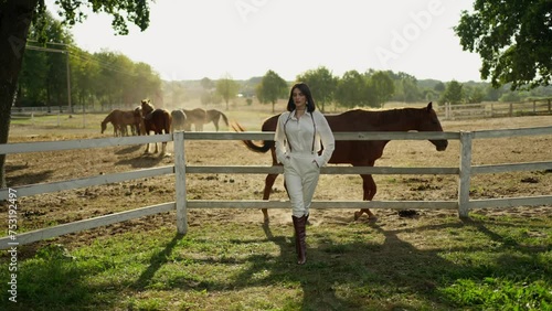 Modern Equestrian Fashion. Fashion-forward woman stands confidently at horse ranch. photo