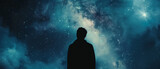 a silhouette of a man standing against the backdrop of a massive, dark blue galaxy in space