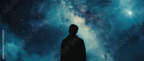 a silhouette of a man standing against the backdrop of a massive, dark blue galaxy in space photo