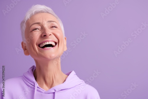 The portrait captures a senior woman's genuine laughter, her spirit as vibrant as the lilac hoodie she wears, radiating happiness and youthful energy.