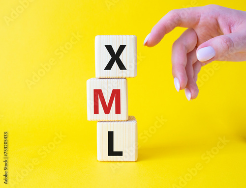 XML - Extensible Markup Language. Wooden cubes with word XML. Businessman hand. Beautiful yellow background. Business and Extensible Markup Language concept. Copy space. photo