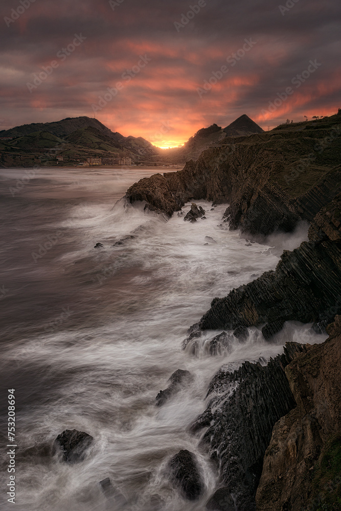Dawn at the tip of the Castle, in Kobaron, Bizkaia, with the waves of the sea crashing forcefully against the cliffs under a beautiful sky of warm colors