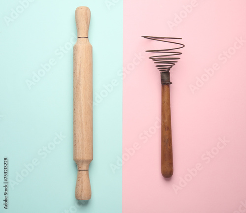Wooden rolling pin and whisk on blue pink pastel background