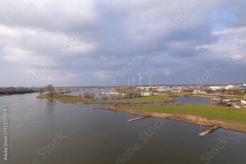River IJssel passing by Dutch Hanseatic city of Zutphen, The Netherlands, with a steel train and traffic draw bridge and new-build neighbourhood Noorderhaven in the foreground