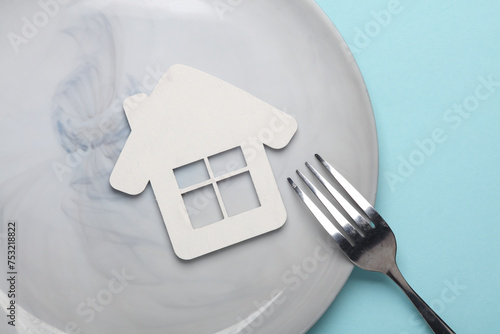 House model in plate with fork on blue background photo