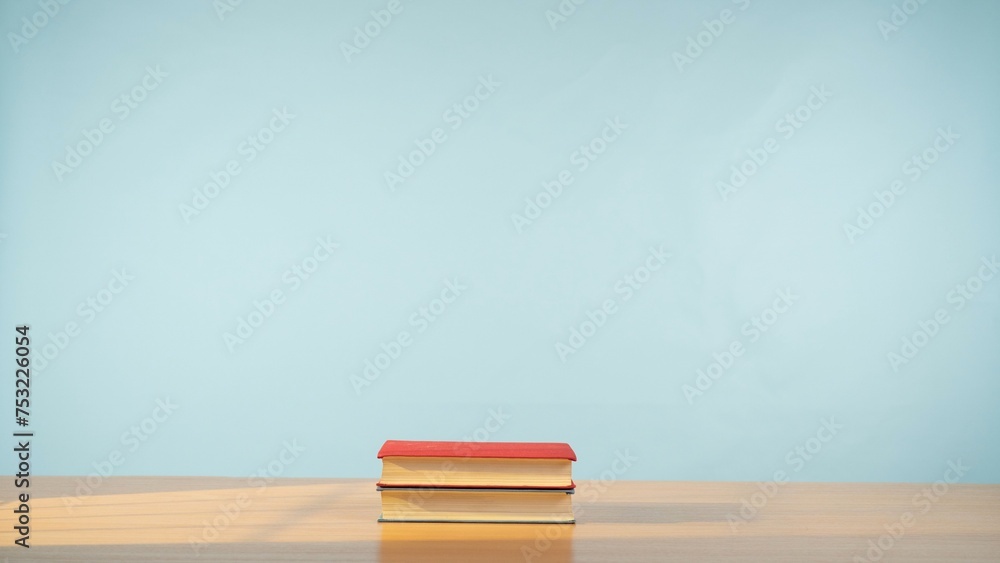 Fototapeta premium Two books on a wooden table on a soothing pastel blue background.