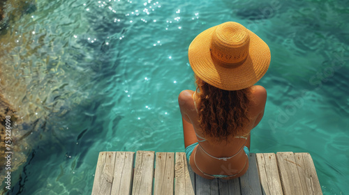 Summer holiday fashion concept - tanning woman wearing sun hat on a wooden pier view from above.